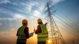 two men looking up at a power grid