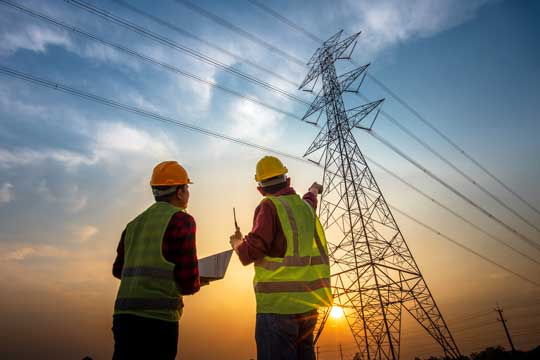 two men looking up at a power grid